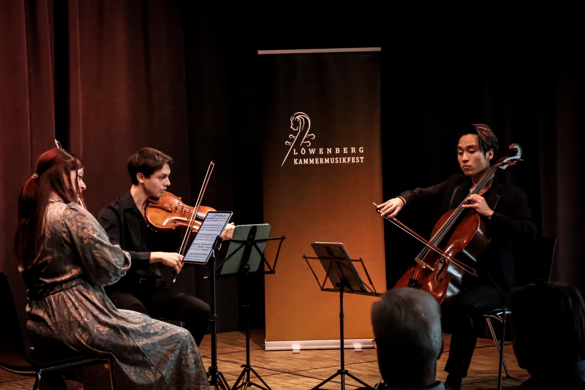 Trio performing in front of the festival banner