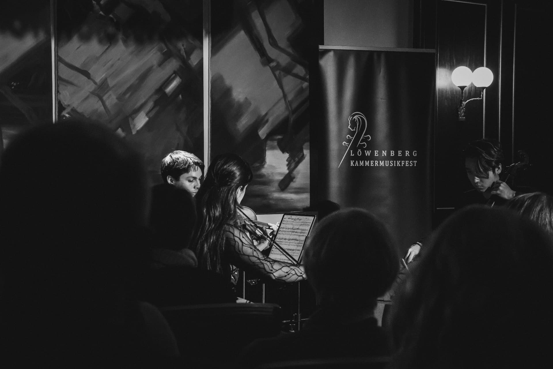 Musicians performing with the festival banner in black and white