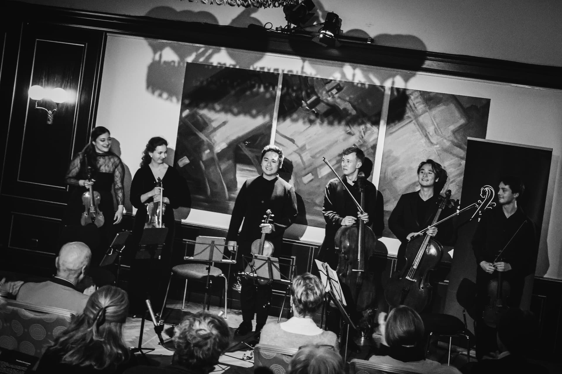 Six musicians taking a bow on stage in black and white
